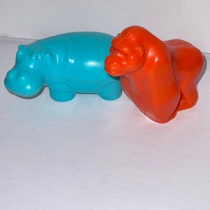 May include: Two plastic animal toys, a blue hippopotamus and an orange gorilla.