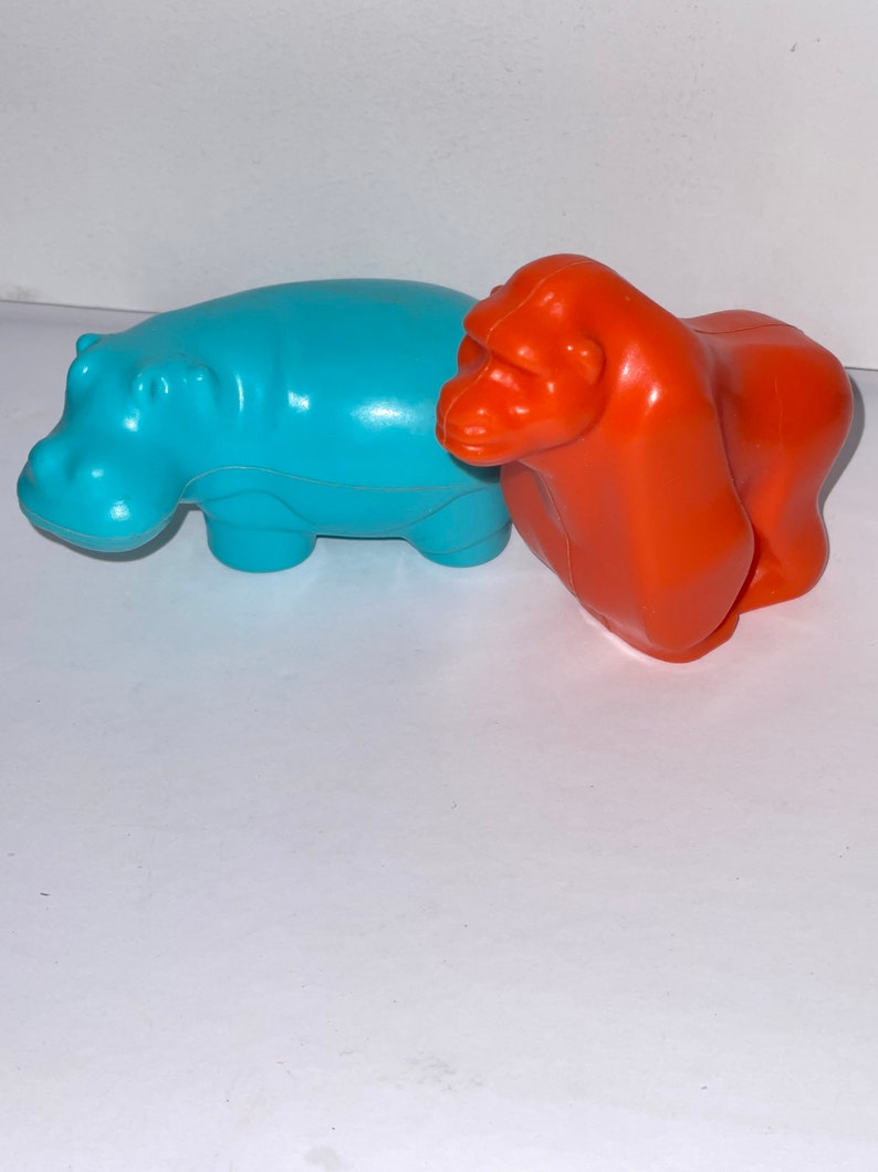 May include: Two plastic animal toys, a blue hippopotamus and an orange gorilla.