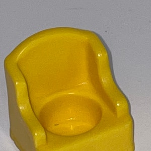 May include: A yellow plastic potty chair for a child. The chair has a rounded back and a seat with a small hole in the centre.