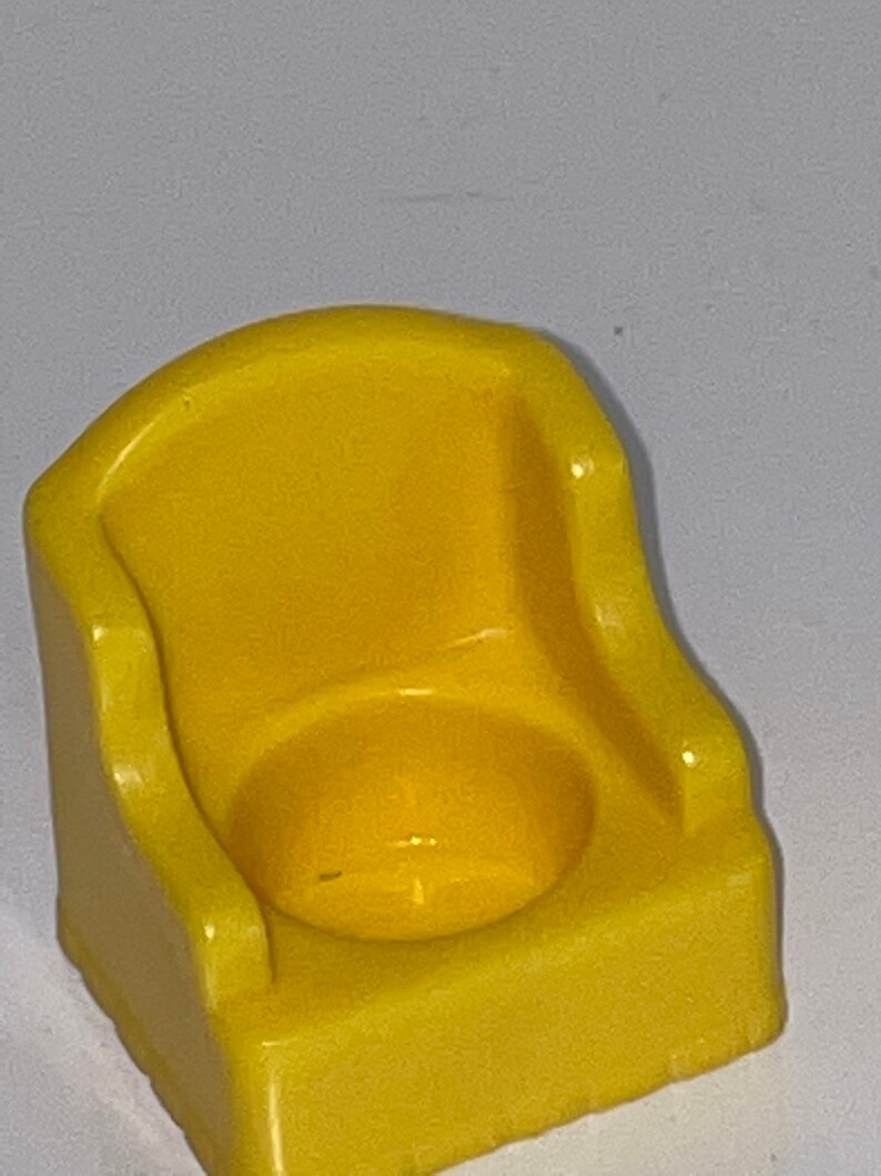 May include: A yellow plastic potty chair for a child. The chair has a rounded back and a seat with a small hole in the centre.