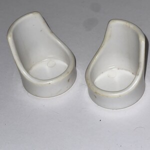 Puede incluir: Dos sillas de casa de mu&ntilde;ecas de pl&aacute;stico blanco. Las sillas son peque&ntilde;as y tienen un dise&ntilde;o sencillo.