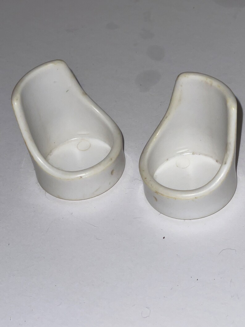 Puede incluir: Dos sillas de casa de mu&ntilde;ecas de pl&aacute;stico blanco. Las sillas son peque&ntilde;as y tienen un dise&ntilde;o sencillo.