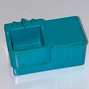 May include: A teal plastic toy kitchen sink with a single basin and two knobs. The sink is designed for play and has a simple, functional design.