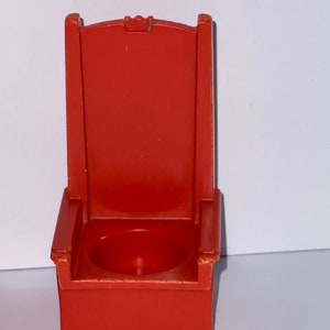 May include: A red plastic throne chair with a small seat and a crown on the back.