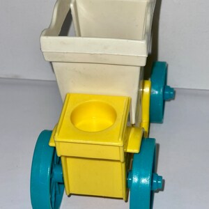 May include: A yellow and white toy carriage with blue wheels. The carriage has a white top and a yellow base with a small cup in the center. The wheels are blue with a white rim.