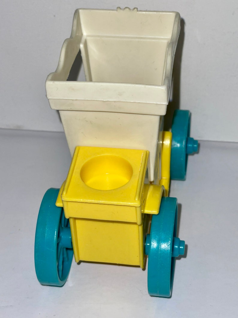 May include: A yellow and white toy carriage with blue wheels. The carriage has a white top and a yellow base with a small cup in the center. The wheels are blue with a white rim.