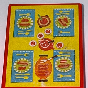 Pu&ograve; includere: Un tavolo da gioco in plastica giallo e rosso con una tovaglia a quadri blu e bianchi. Il tavolo ha una pentola rossa con manico, quattro piatti con hot dog e una griglia con salsicce.