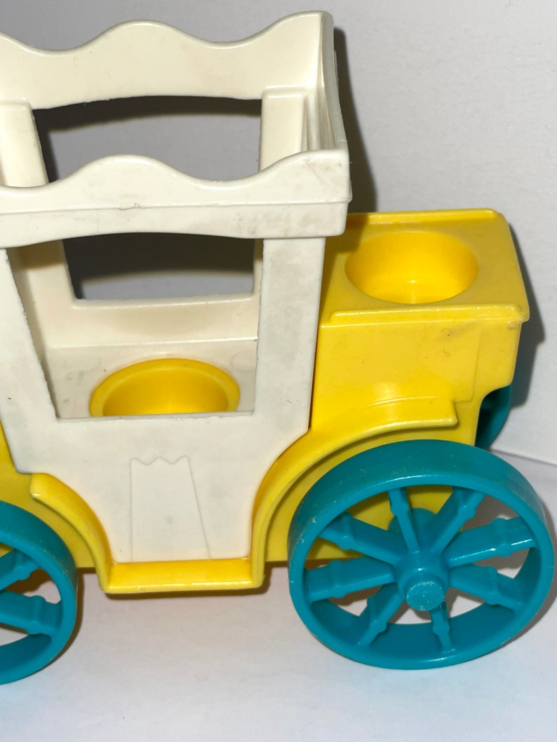 May include: A yellow and white toy carriage with blue wheels. The carriage has a white roof and two yellow seats.