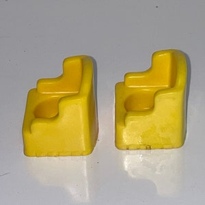 May include: Two yellow plastic chairs with a small hole in the back of each seat. The chairs are designed for small children.