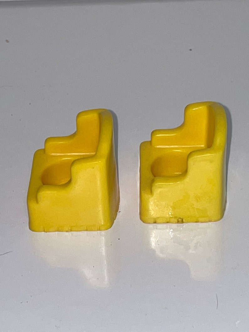 May include: Two yellow plastic chairs with a small hole in the back of each seat. The chairs are designed for small children.