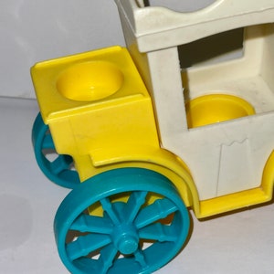 May include: A vintage toy wagon with a white body, yellow sides, and blue wheels. The wagon has a removable top and two yellow cup holders.