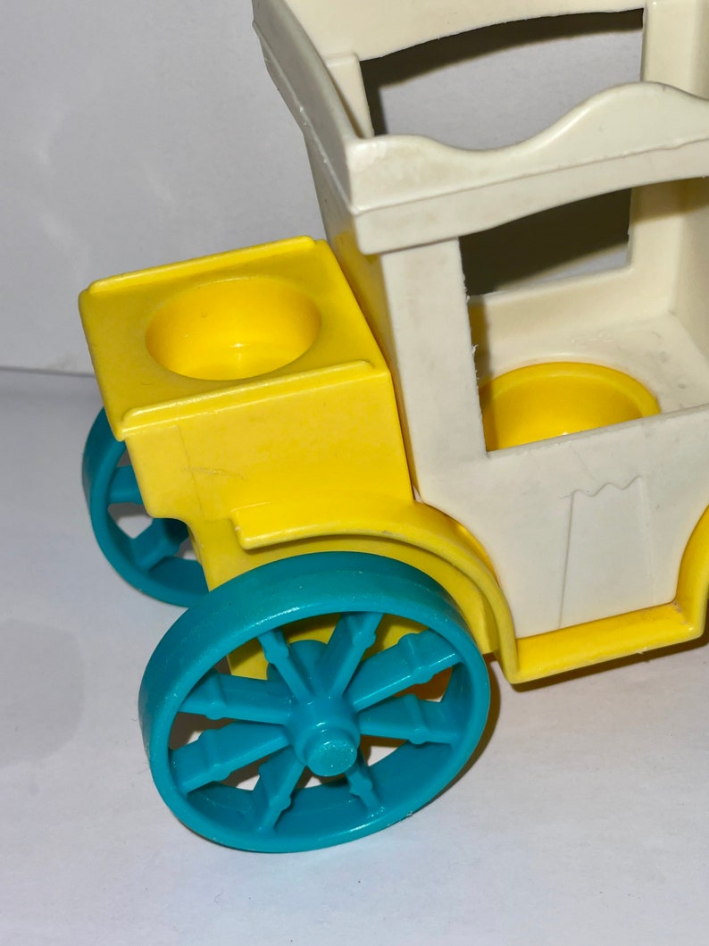 May include: A vintage toy wagon with a white body, yellow sides, and blue wheels. The wagon has a removable top and two yellow cup holders.