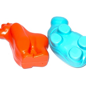 May include: Two plastic animal toys, one orange and one blue. The orange toy is shaped like a bear and the blue toy is shaped like a hippopotamus.