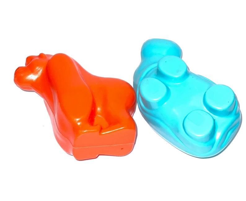 May include: Two plastic animal toys, one orange and one blue. The orange toy is shaped like a bear and the blue toy is shaped like a hippopotamus.