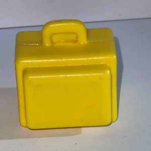 K&ouml;nnte beinhalten: Ein kleiner, leuchtend gelber Plastikkoffer mit einem Griff oben.