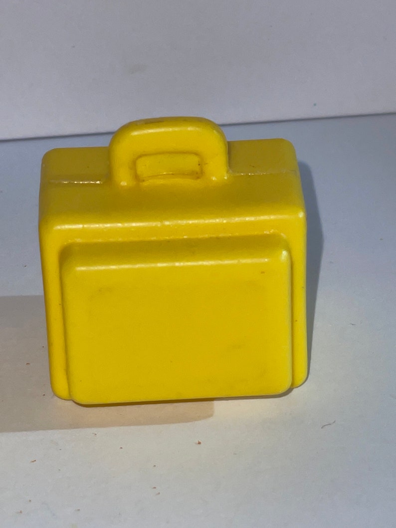 K&ouml;nnte beinhalten: Ein kleiner, leuchtend gelber Plastikkoffer mit einem Griff oben.