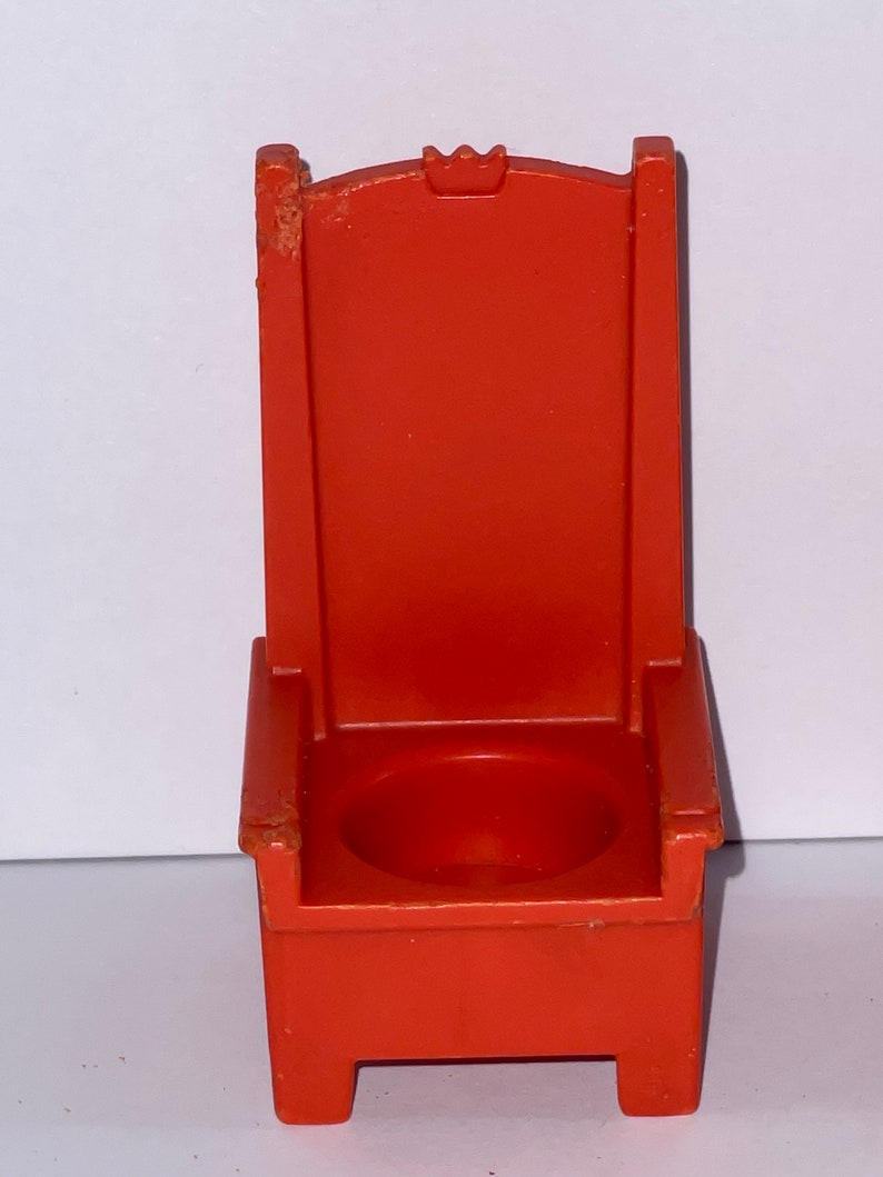 May include: A red plastic throne chair with a crown on the back. The chair has a small seat and four legs.