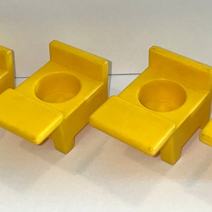 May include: Four yellow plastic children's chairs with a small desk attached to the front of each chair.