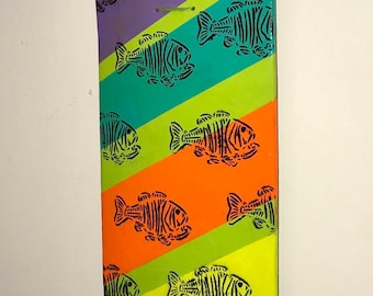 Serigrafía original de esqueleto de pez sobre tabla de skate pintada con el arte “Death spawn”