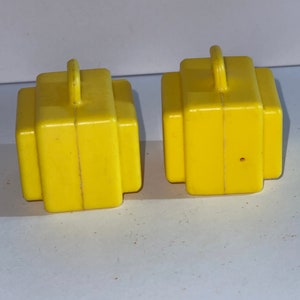 K&ouml;nnte beinhalten: Zwei gelbe Spielzeugkoffer aus Plastik mit Griffen oben. Die Koffer sind etwa 5 cm hoch und 4 cm breit.