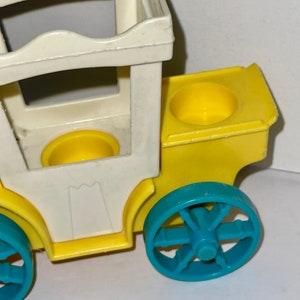 May include: A yellow and white plastic toy carriage with blue wheels. The carriage has two yellow cup holders and a white roof.