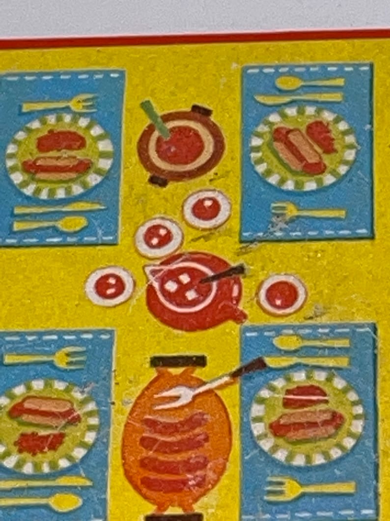 Pu&ograve; includere: Una tavola apparecchiata con tovagliette azzurre, piatti rossi e bianchi e una ciotola rossa con un cucchiaio. Ci sono anche quattro piccole ciotole rosse con puntini bianchi sul tavolo.