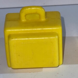 K&ouml;nnte beinhalten: Ein gelber Plastik-Spielzeugkoffer mit einem Griff oben.