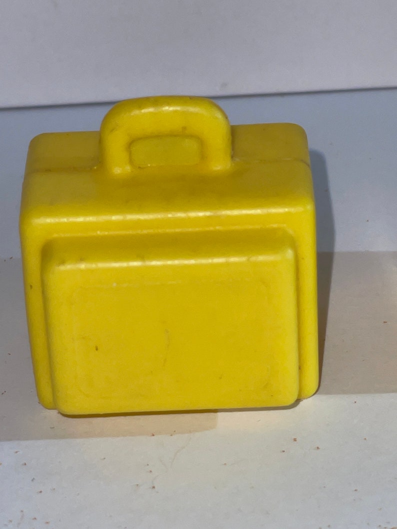K&ouml;nnte beinhalten: Ein gelber Plastik-Spielzeugkoffer mit einem Griff oben.