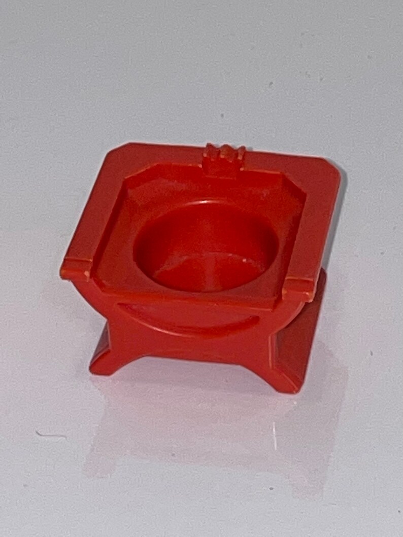 May include: A red plastic toy throne with a round seat and a crown on top.