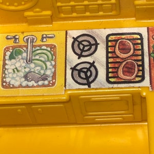 K&ouml;nnte beinhalten: Ein gelbes Spielzeug-K&uuml;chenset aus Plastik mit Sp&uuml;le, Herd, Backofen und Schr&auml;nken. Die Sp&uuml;le hat einen Wasserhahn und einen Schwamm. Der Herd hat zwei Kochfelder und einen Grill. Der Backofen hat eine T&uuml;r. Die Schr&auml;nke haben T&uuml;ren.