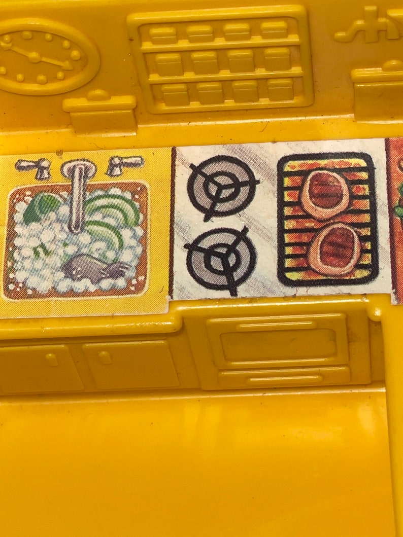 K&ouml;nnte beinhalten: Ein gelbes Spielzeug-K&uuml;chenset aus Plastik mit Sp&uuml;le, Herd, Backofen und Schr&auml;nken. Die Sp&uuml;le hat einen Wasserhahn und einen Schwamm. Der Herd hat zwei Kochfelder und einen Grill. Der Backofen hat eine T&uuml;r. Die Schr&auml;nke haben T&uuml;ren.