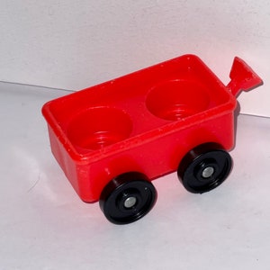 May include: A red toy wagon with two black wheels and a handle. The wagon has two empty compartments.