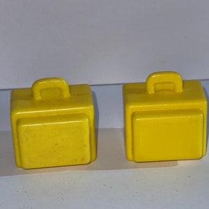 K&ouml;nnte beinhalten: Zwei gelbe Spielzeugkoffer aus Plastik mit Griffen. Die Koffer sind etwa 5 cm hoch und 5 cm breit.