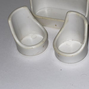 Puede incluir: Un conjunto de tres muebles de casa de mu&ntilde;ecas de pl&aacute;stico blanco, que incluye un sof&aacute; y dos sillas.