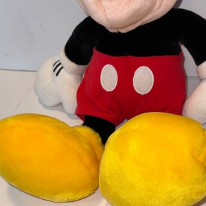 May include: A plush Mickey Mouse toy with black fur, red shorts with white circles, and yellow shoes.