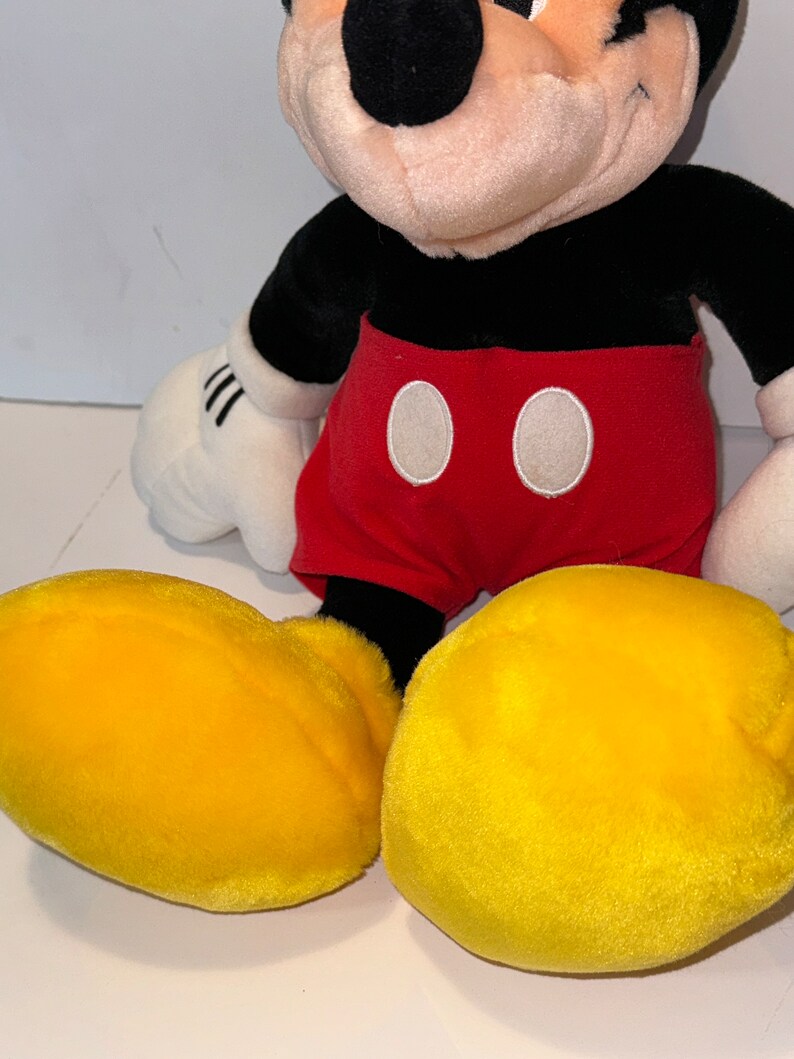 May include: A plush Mickey Mouse toy with black fur, red shorts with white circles, and yellow shoes.