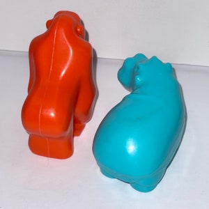 May include: Two plastic animal figurines, a bright orange gorilla and a turquoise blue hippopotamus.