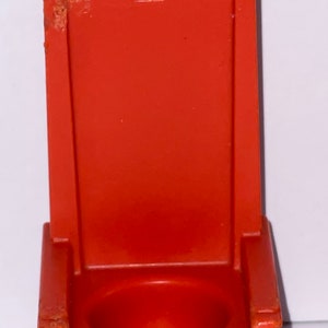 May include: Orange plastic toy throne with a crown on the back. The throne has a round seat.