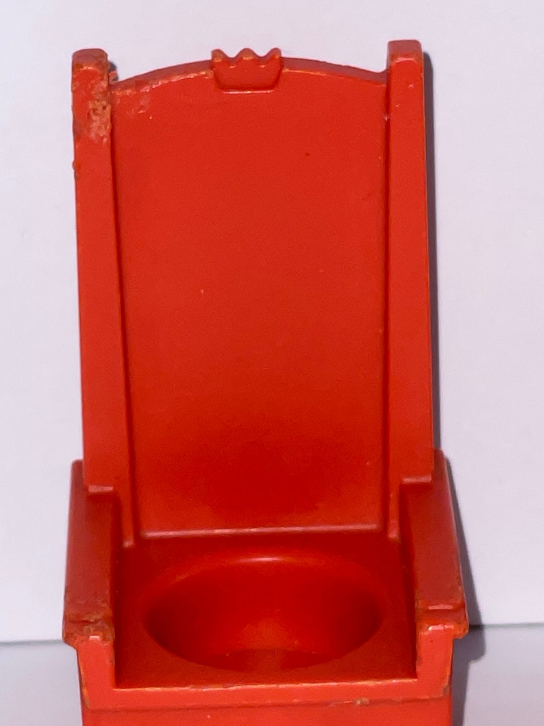 May include: Orange plastic toy throne with a crown on the back. The throne has a round seat.