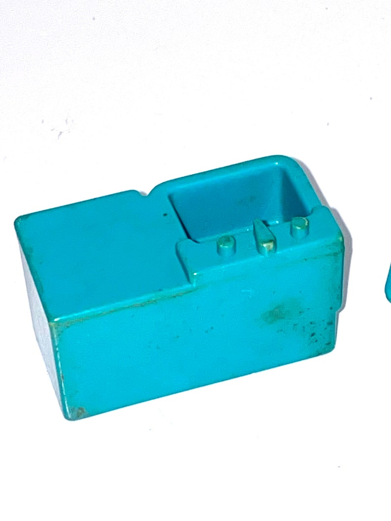 May include: A turquoise blue plastic toy kitchen sink with a countertop and three knobs.
