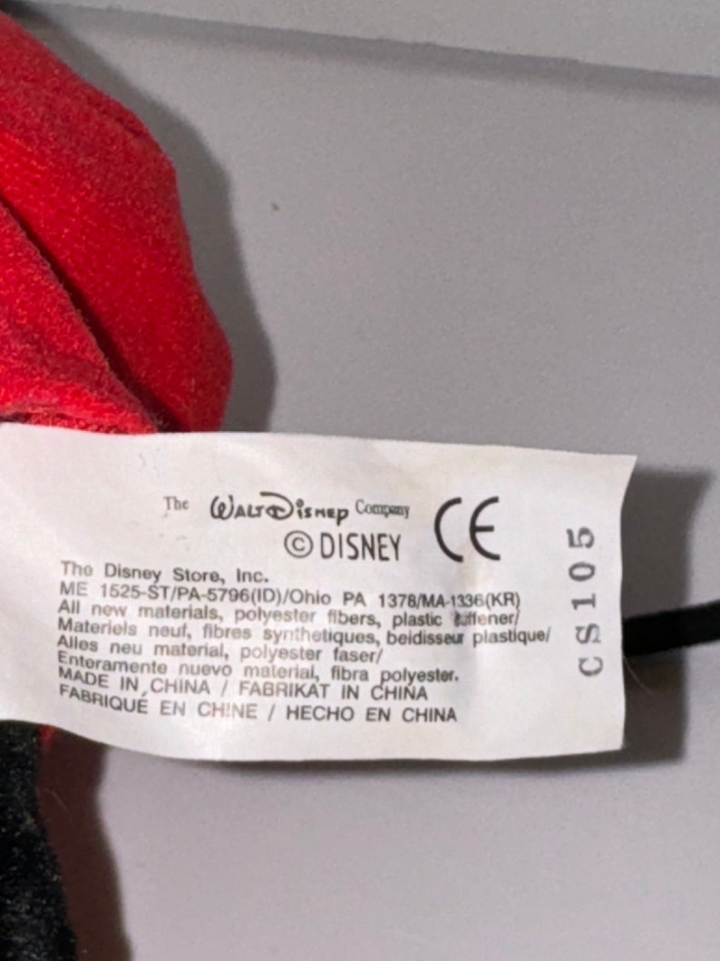 May include: White tag with black text. The Walt Disney Company, &copy;DISNEY, CE, CS105. The Disney Store, Inc. ME 1525-ST/PA-5796(ID)/Ohio PA 1378/MA-1336(KR) All new materials, polyester fibers, plastic stiffener. Materiels neuf, fibres synthetiques, beidisseur plastique/ Alles neu material, polyester faser/ Enteramente nuevo material, fibra polyester. MADE IN CHINA FABRIKAT IN CHINA FABRIQUE EN CHINE / HECHO EN CHINA