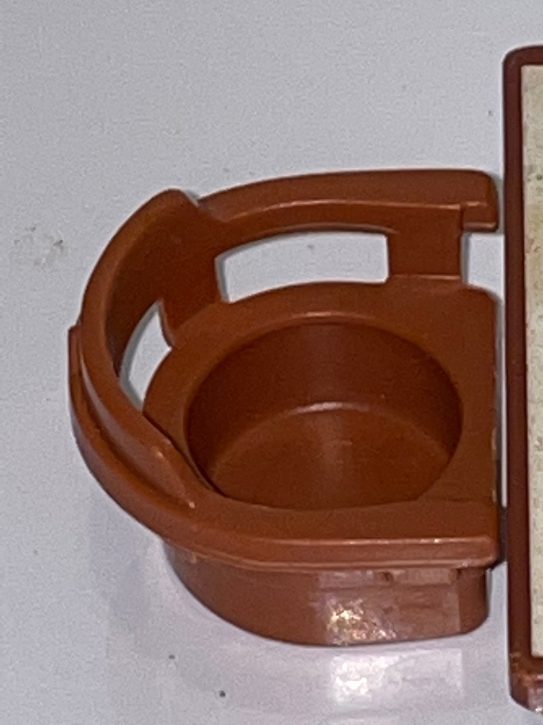 May include: A brown plastic toy chair with a rounded back and a small seat. The chair is designed to fit a small doll or action figure.