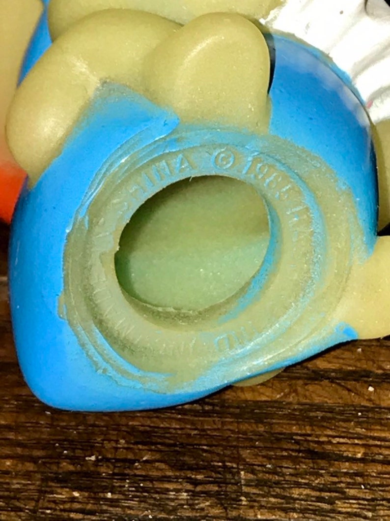 Puede incluir: Primer plano de un juguete de pl&aacute;stico azul y amarillo con las palabras "CHINA &copy; 1987" impresas en la parte inferior.