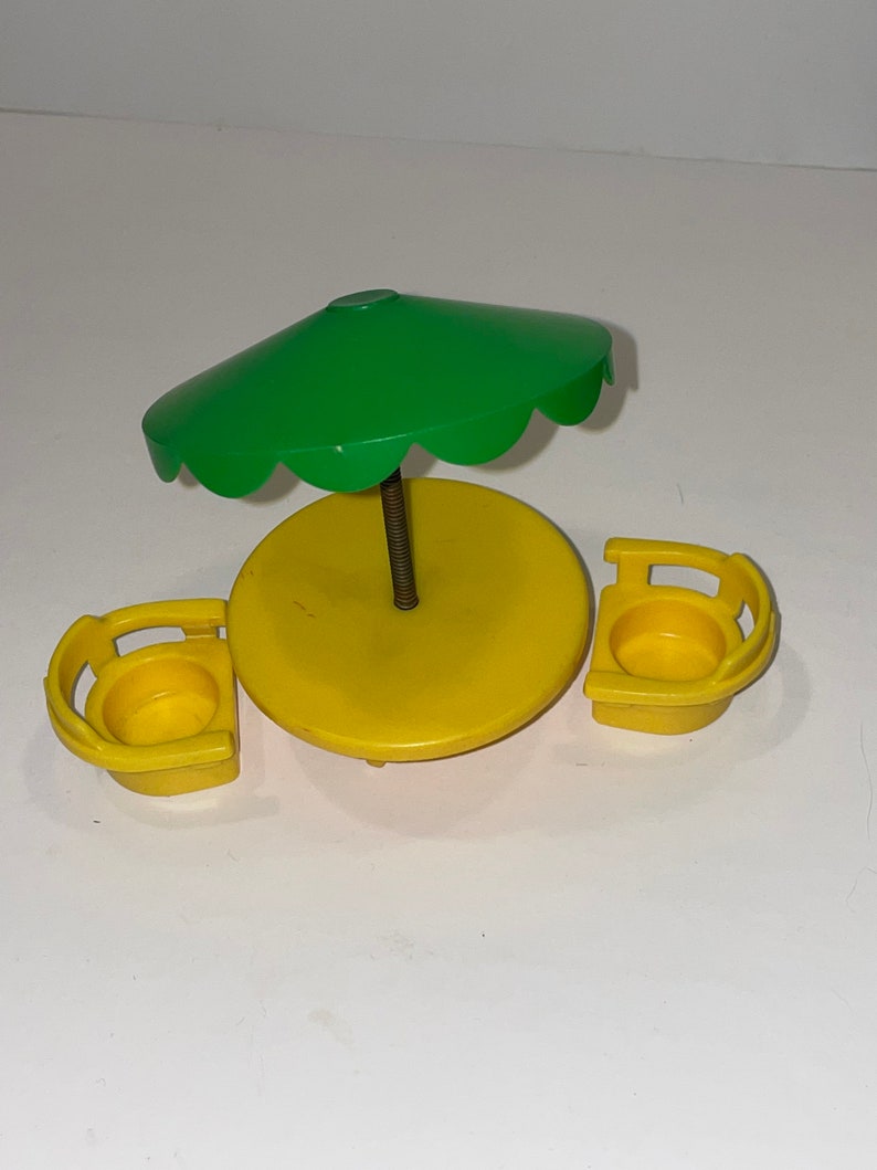 May include: A yellow plastic table and two chairs with a green umbrella. The table and chairs are designed for small children.