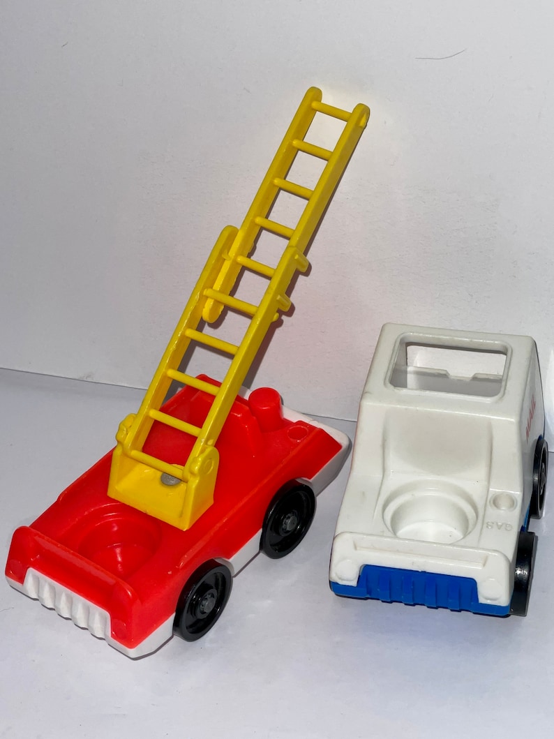 May include: A red and white fire truck with a yellow ladder and a white and blue van. Both vehicles have black wheels.