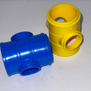 May include: Two plastic toy building blocks, one blue and one yellow. The blue block has four openings, while the yellow block has three openings.