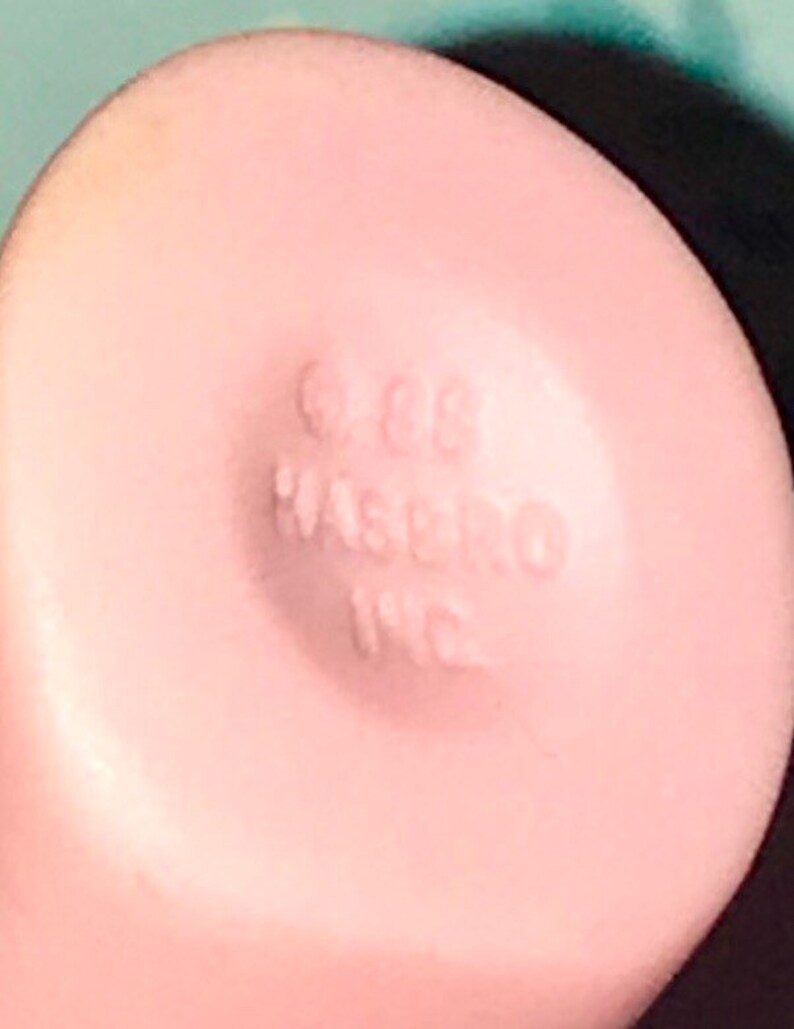 Puede incluir: Primer plano de un juguete de pl&aacute;stico rosa con el texto "1988 Hasbro Inc." impreso en la parte inferior.