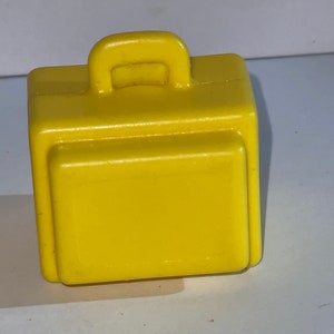 K&ouml;nnte beinhalten: Ein gelber Plastik-Spielzeugkoffer mit einem Griff oben. Der Koffer ist ein kleines Spielzeug f&uuml;r Kinder.