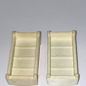 May include: Two white plastic toy storage bins with four compartments each. The bins are empty and have a slightly rounded bottom.