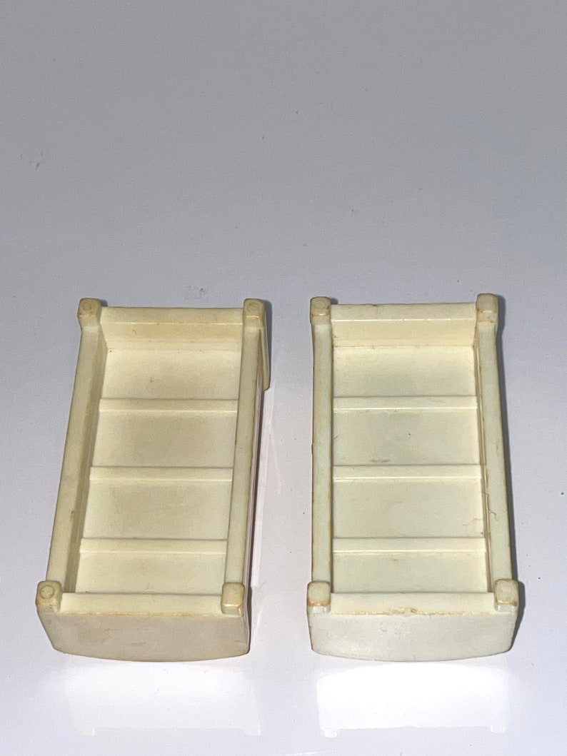 May include: Two white plastic toy storage bins with four compartments each. The bins are empty and have a slightly rounded bottom.